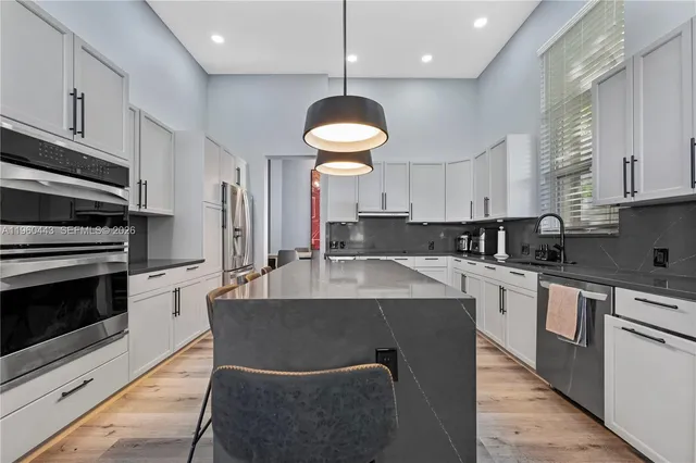 a kitchen with kitchen island stainless steel appliances a stove sink microwave and cabinets