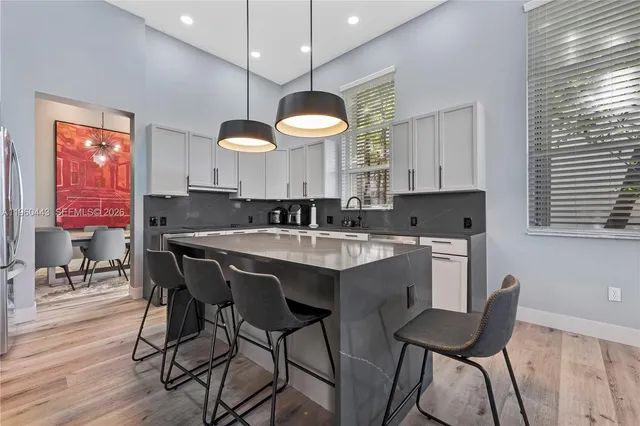 a kitchen with a dining table chairs sink and white cabinets