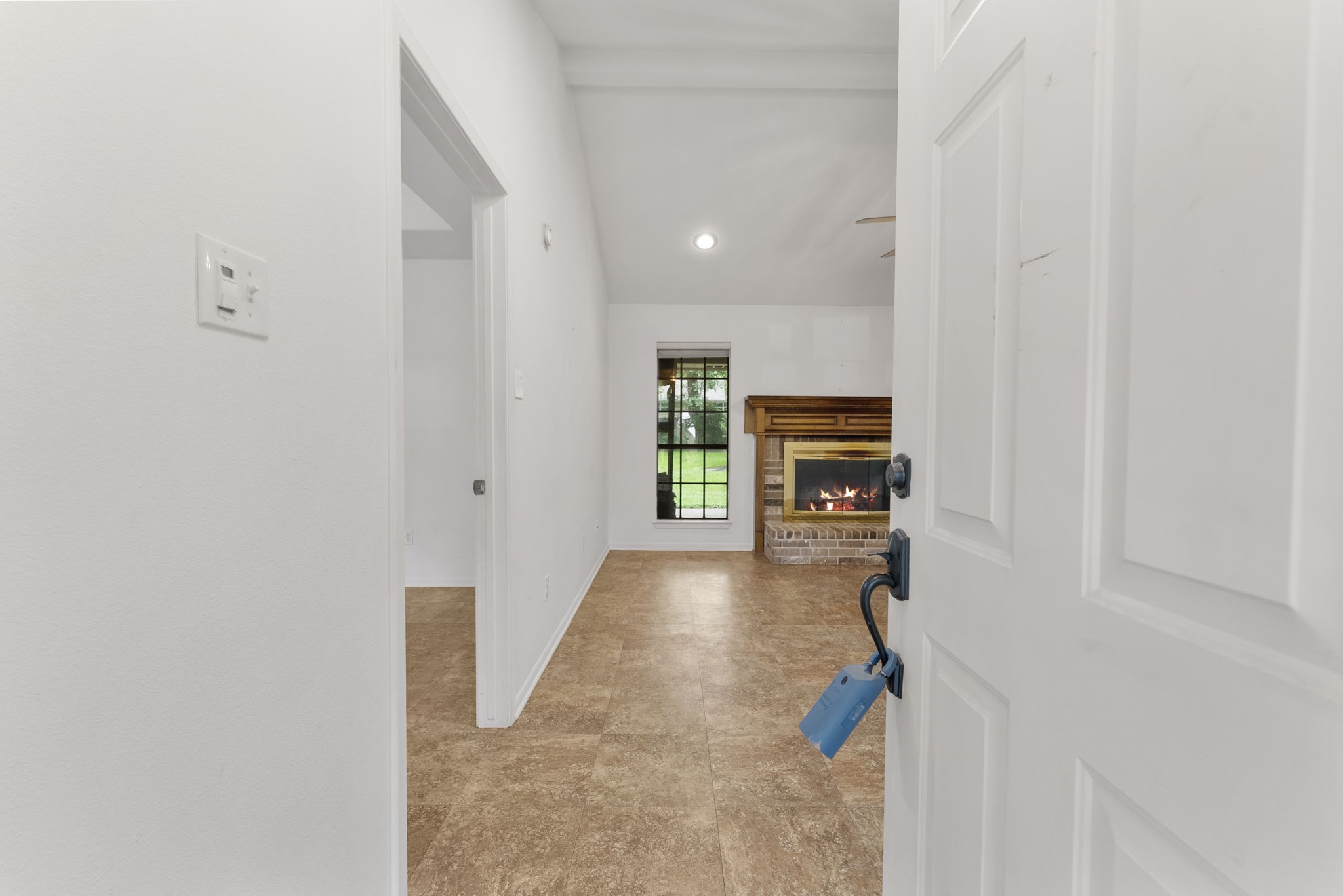 202 Sunset Boulevard Conroe, TX 77303 - Photo 7 of 50 Welcome home to a charming foyer entry that gracefully opens into a warm living space, highlighted by a cozy fireplace and a window overlooking lush greenery.