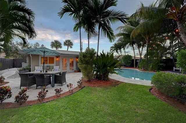 a view of a patio with table and chairs potted plants and palm tree