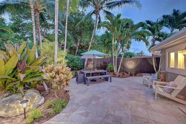 a backyard of a house with table and chairs under an umbrella