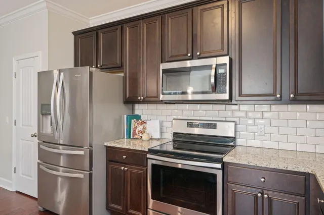 a kitchen with granite countertop a refrigerator stove and microwave