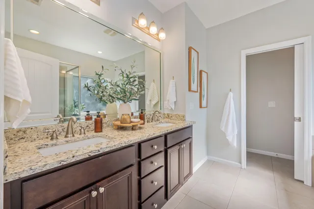 a bathroom with a granite countertop double vanity sink and a mirror