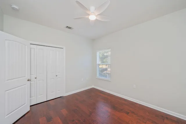 a view of an empty room with a window and wooden floor