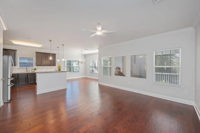a view of an empty room with kitchen and window