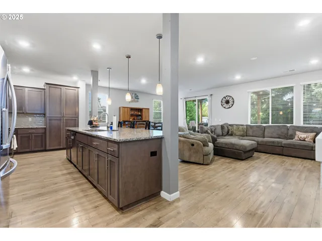 a kitchen with stainless steel appliances kitchen island granite countertop a sink a counter top space and living room view