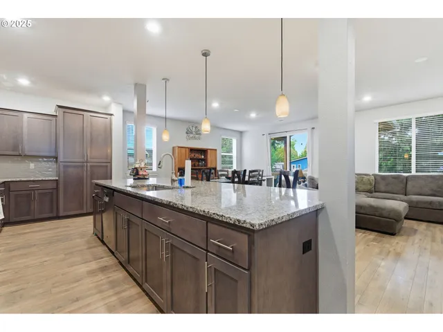 a kitchen with stainless steel appliances kitchen island granite countertop a table chairs microwave and sink