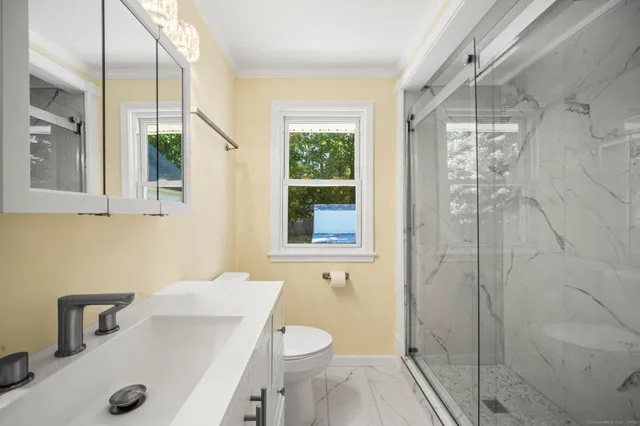 a bathroom with a sink a toilet window and shower