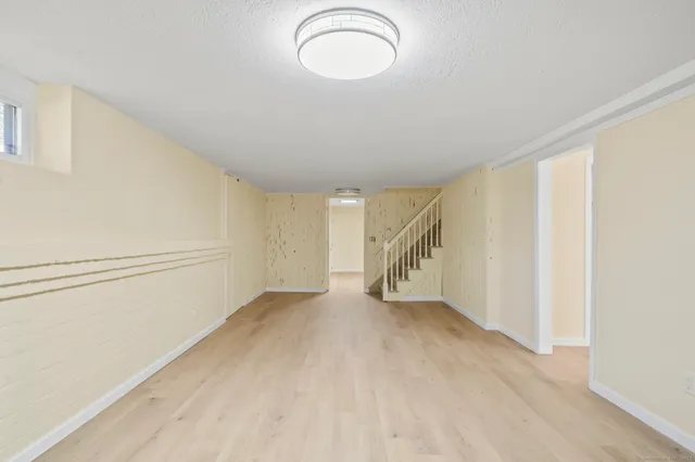 a view of an empty room with wooden floor and window