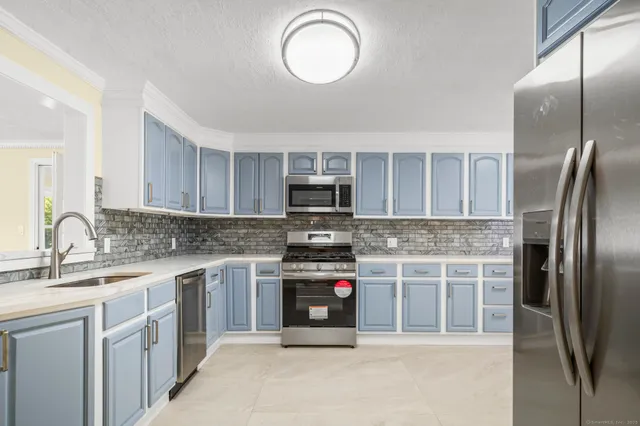 a kitchen with stainless steel appliances granite countertop a stove top oven a sink and a refrigerator