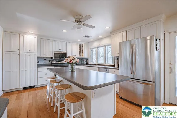 a kitchen with stainless steel appliances granite countertop a refrigerator a stove and a sink with wooden floor