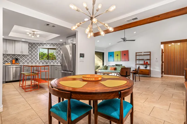 a dining room with stainless steel appliances kitchen island granite countertop a table chairs and a chandelier