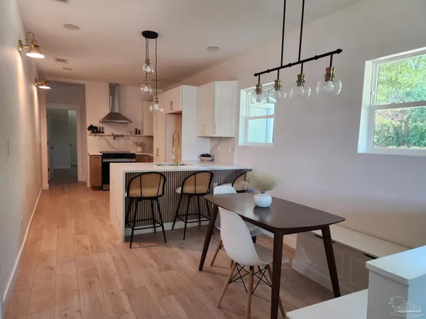 a kitchen with stainless steel appliances granite countertop a dining table chairs and white cabinets