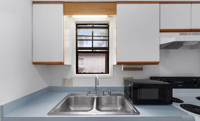 a kitchen with sink a microwave and cabinets