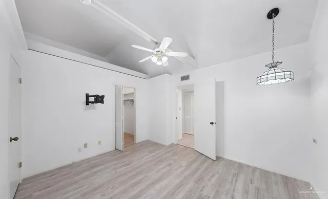 a view of an empty room with chandelier fan