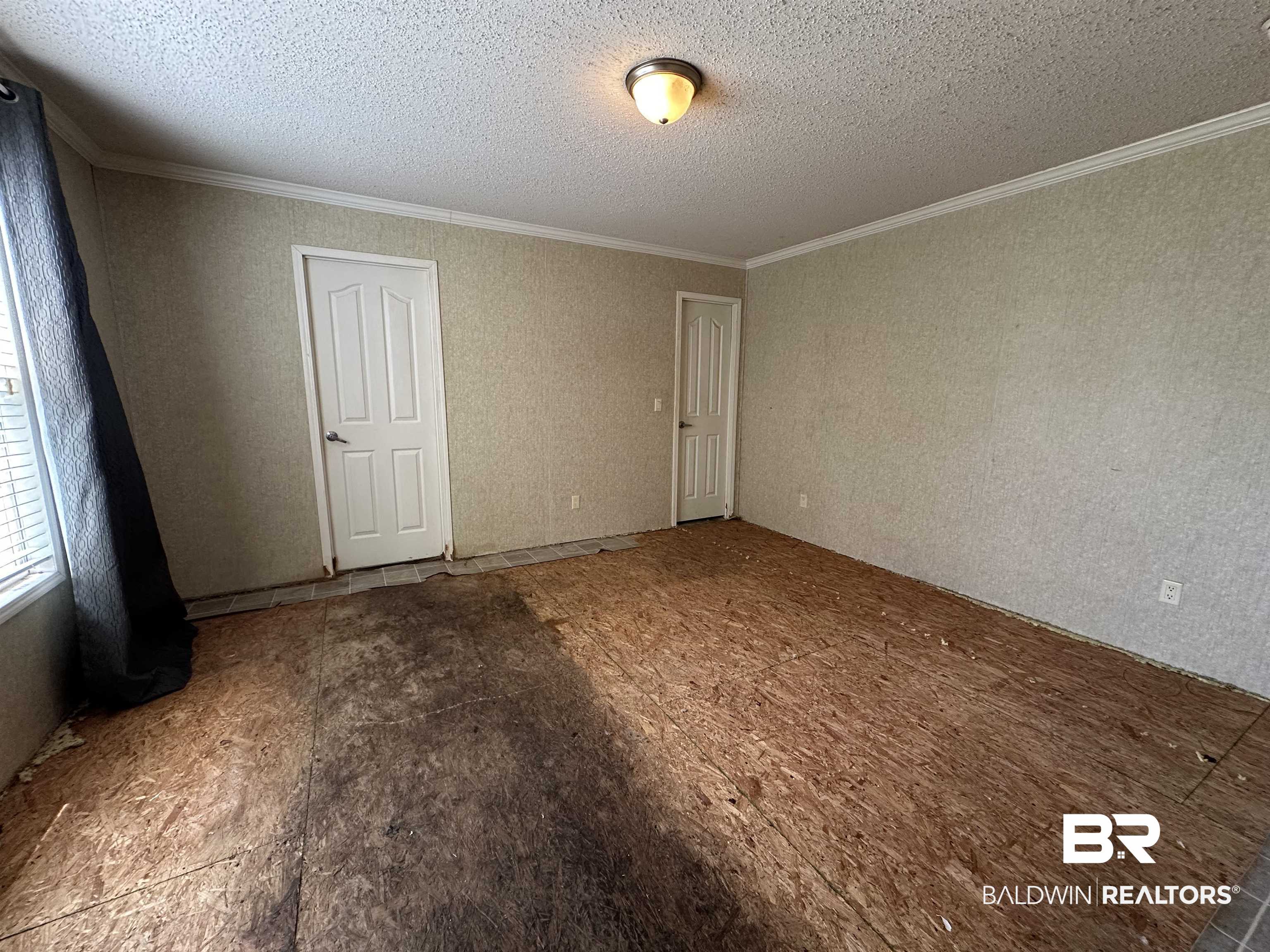 23268 T D Barnett Road Robertsdale, AL 36567 - Photo 12 of 16 Unfurnished bedroom with ornamental molding and a textured ceiling
