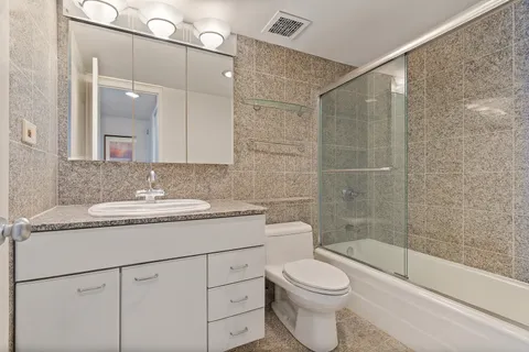 a bathroom with a granite countertop sink toilet and shower