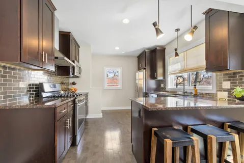 a kitchen with stainless steel appliances granite countertop a sink a stove and a refrigerator