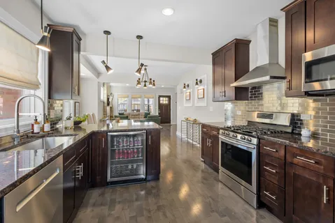 a kitchen with stainless steel appliances granite countertop a stove top oven a sink dishwasher a refrigerator and a oven with wooden floor