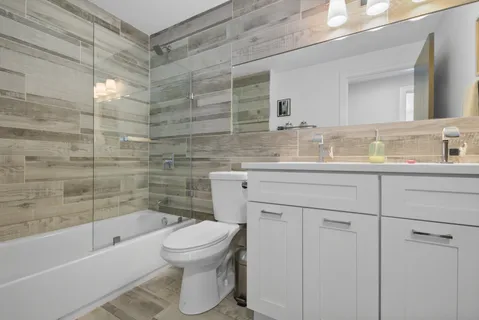 a bathroom with a bathtub shower sink mirror vanity and toilet