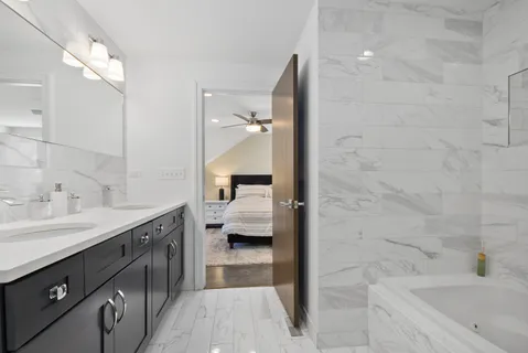 a spacious bathroom with a tub sink and mirror