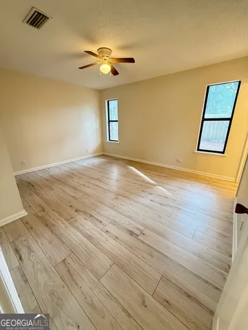 a view of an empty room with wooden floor and a window