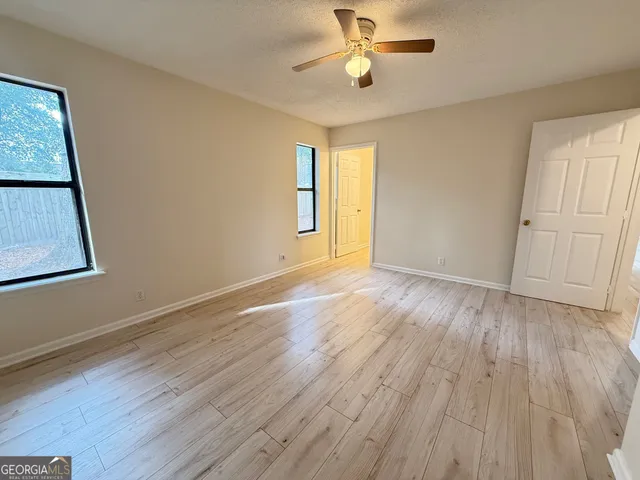 a view of empty room with wooden floor and fan