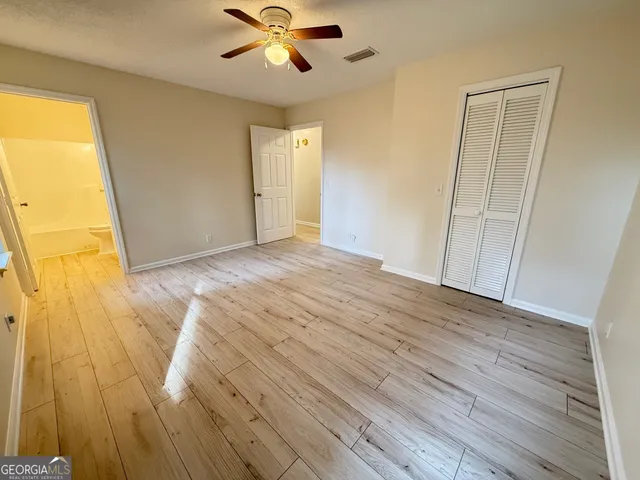 a view of empty room with wooden floor and fan