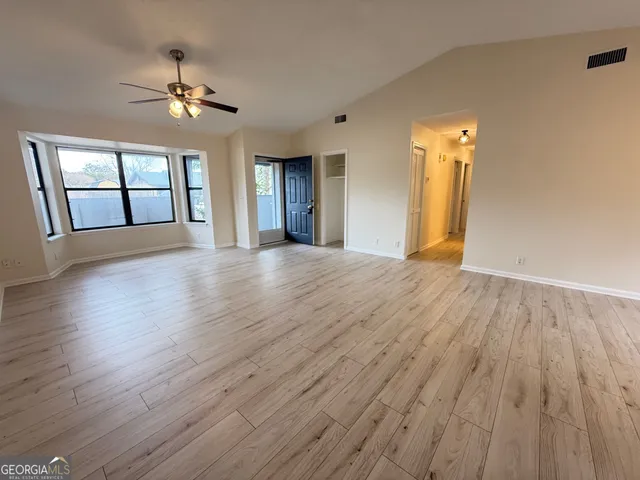 a view of an empty room with wooden floor and a window