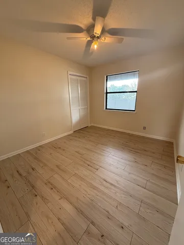 an empty room with wooden floor fan and windows
