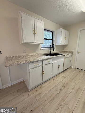 a kitchen with granite countertop white cabinets white appliances and sink