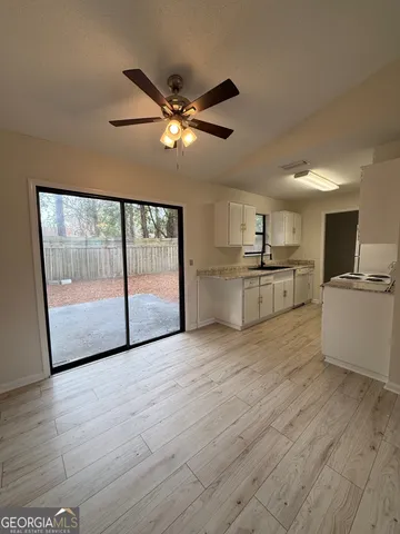 a view of a kitchen with wooden floor electronic appliances and furniture