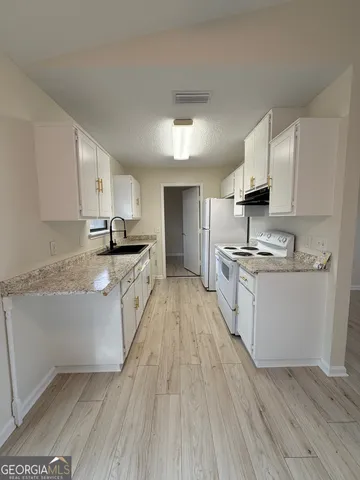 a kitchen with granite countertop a sink a counter top space stainless steel appliances and cabinets