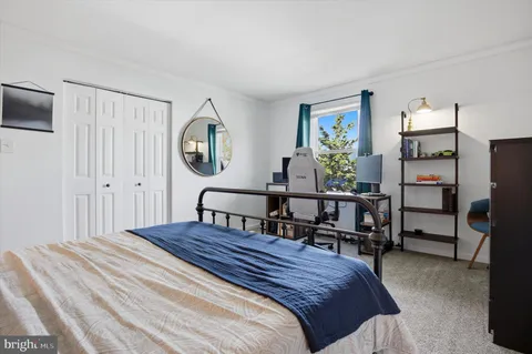 a bedroom with a bed table closet and a window