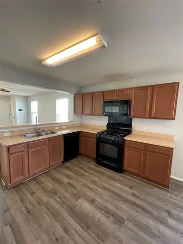 a view of an empty room with wooden floor and a ceiling fan