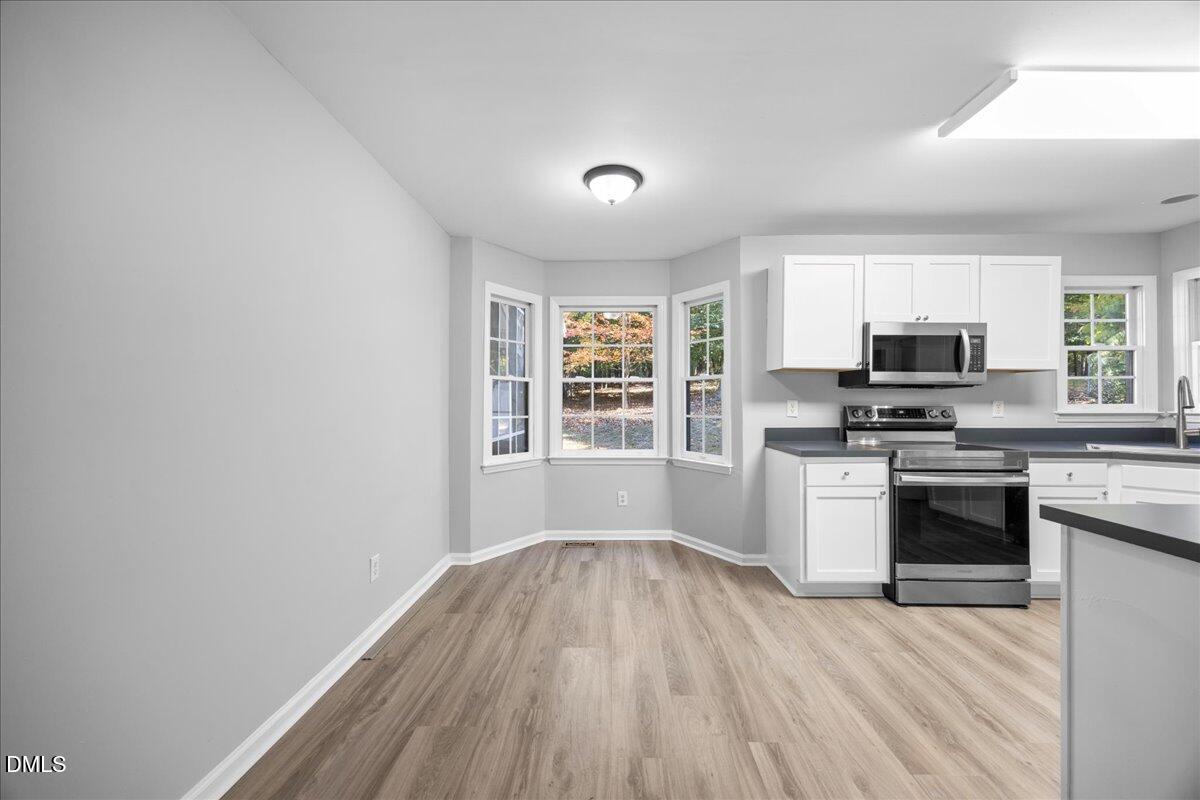 2708 Ferrand Drive Durham, NC 27705 - Photo 11 of 47 a kitchen with granite countertop a stove top oven a sink dishwasher a microwave oven with cabinets and wooden floor
