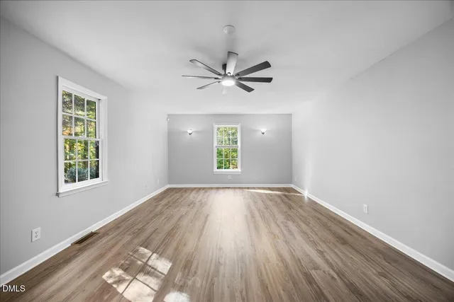 a view of empty room with wooden floor and fan
