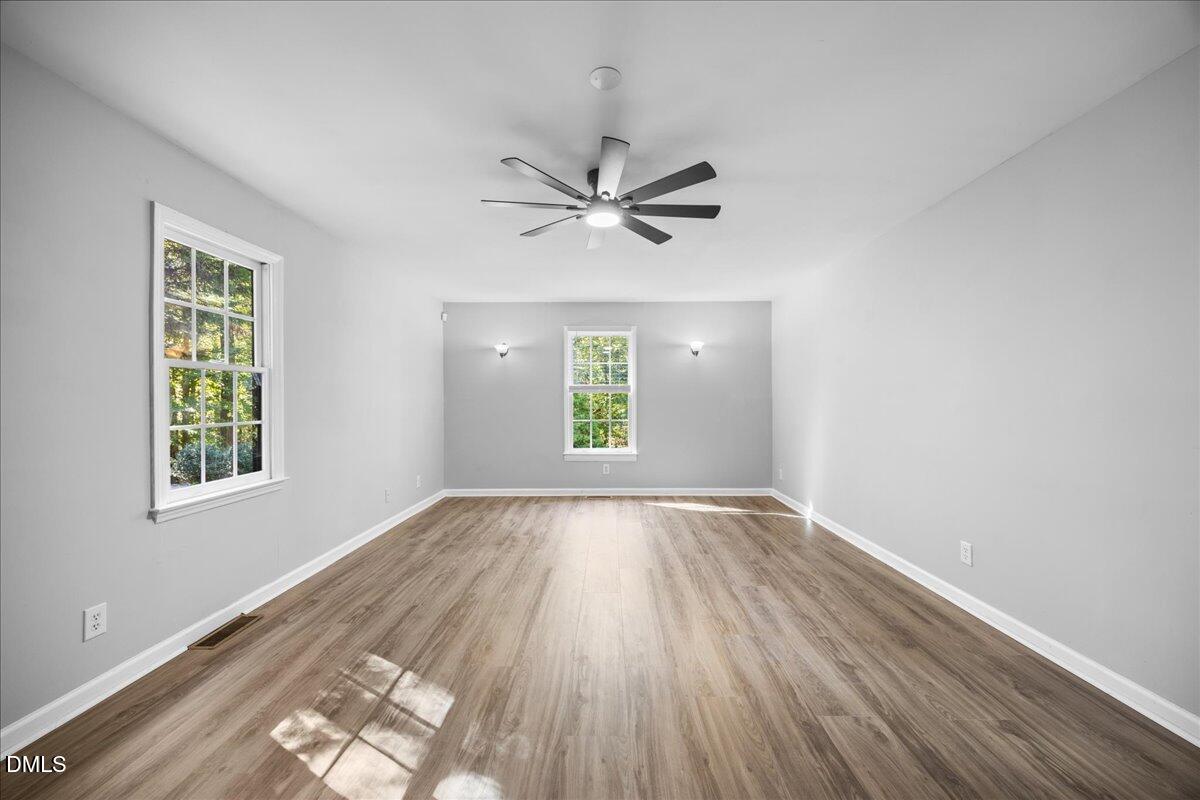 2708 Ferrand Drive Durham, NC 27705 - Photo 18 of 47 an empty room with wooden floor chandelier fan and windows