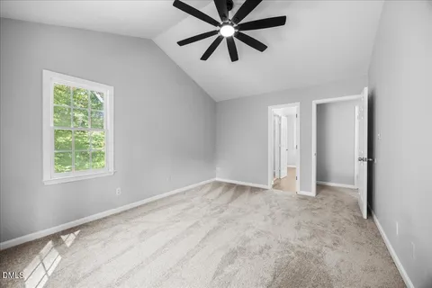 an empty room with wooden floor chandelier fan and windows