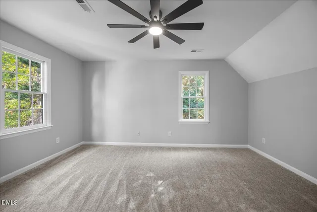 an empty room with ceiling fan and windows