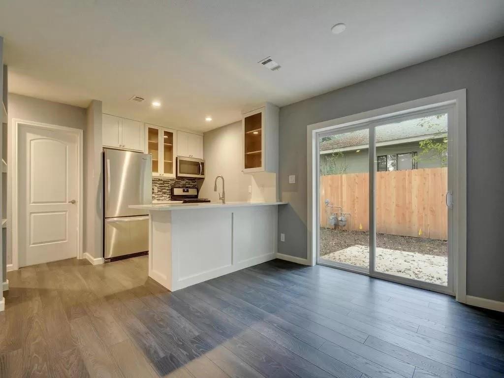 4702 Duval Street Austin, TX 78751 - Photo 3 of 20 a kitchen with stainless steel appliances a refrigerator and wooden floor