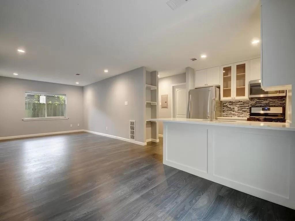 4702 Duval Street Austin, TX 78751 - Photo 5 of 20 an empty room with wooden floor kitchen view and windows