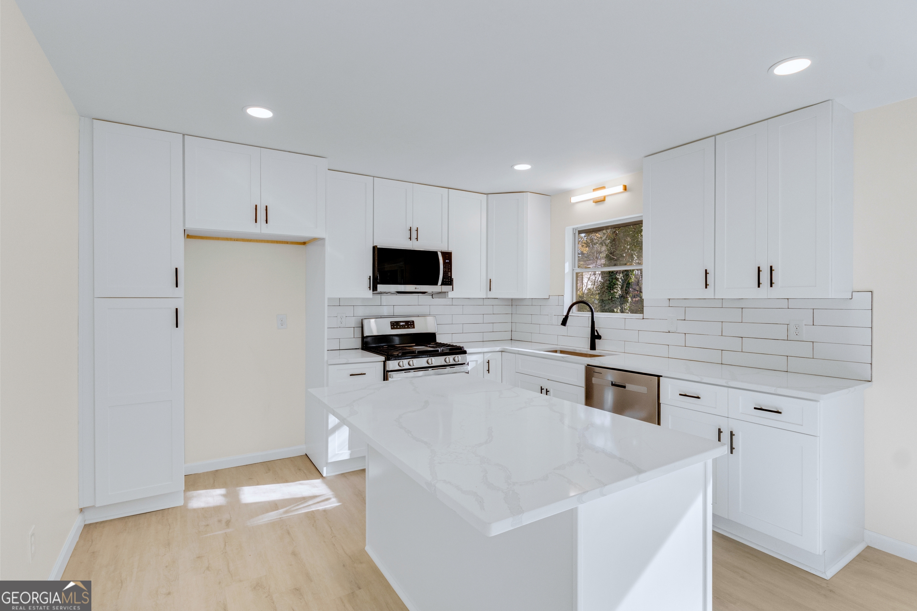 6695 Cedar Hurst Trail Atlanta, GA 30349 - Photo 9 of 23 a large white kitchen with a stove a sink a refrigerator and white cabinets with wooden floor