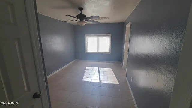 en empty room with window and chandelier fan