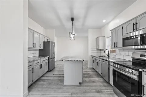 a kitchen with stainless steel appliances a stove top oven a sink dishwasher and a refrigerator