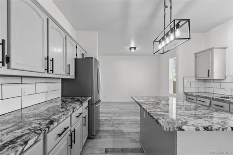 a kitchen with kitchen island granite countertop a sink stove and refrigerator