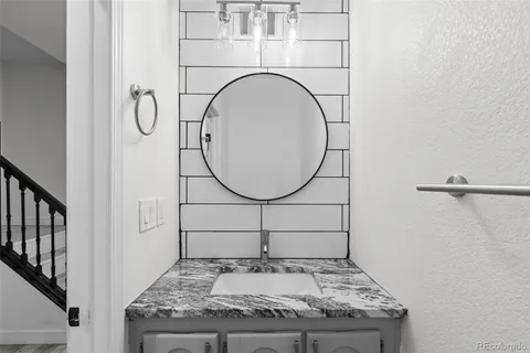a bathroom with a granite countertop sink a mirror and a shower