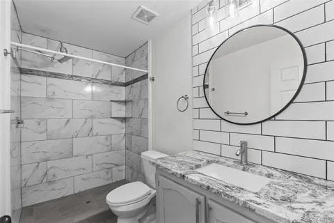a bathroom with a granite countertop sink a toilet and a mirror