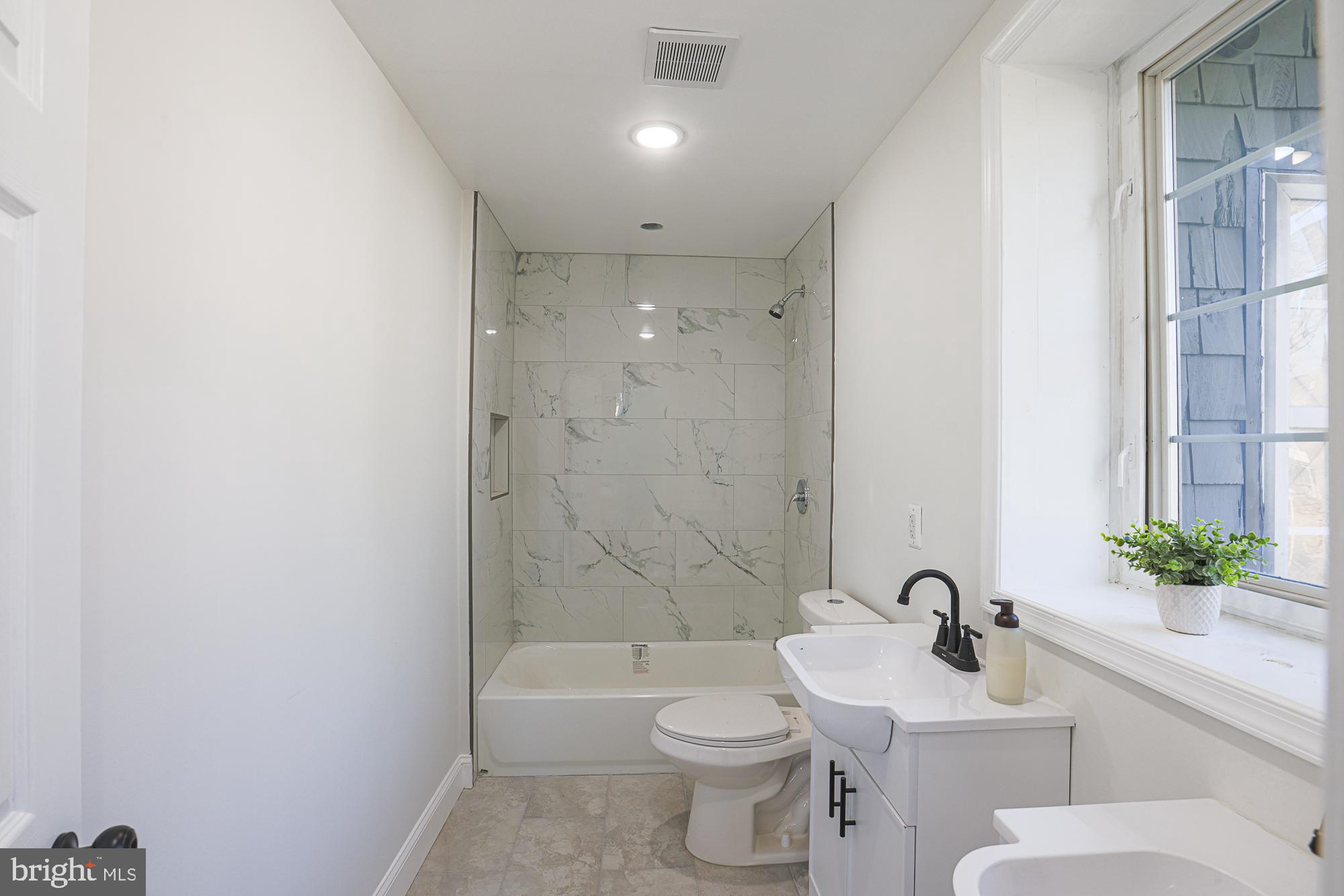 2606 Queen Anne Road Baltimore, MD 21216 - Photo 69 of 92 a bathroom with a toilet a sink a mirror a bathtub and shower