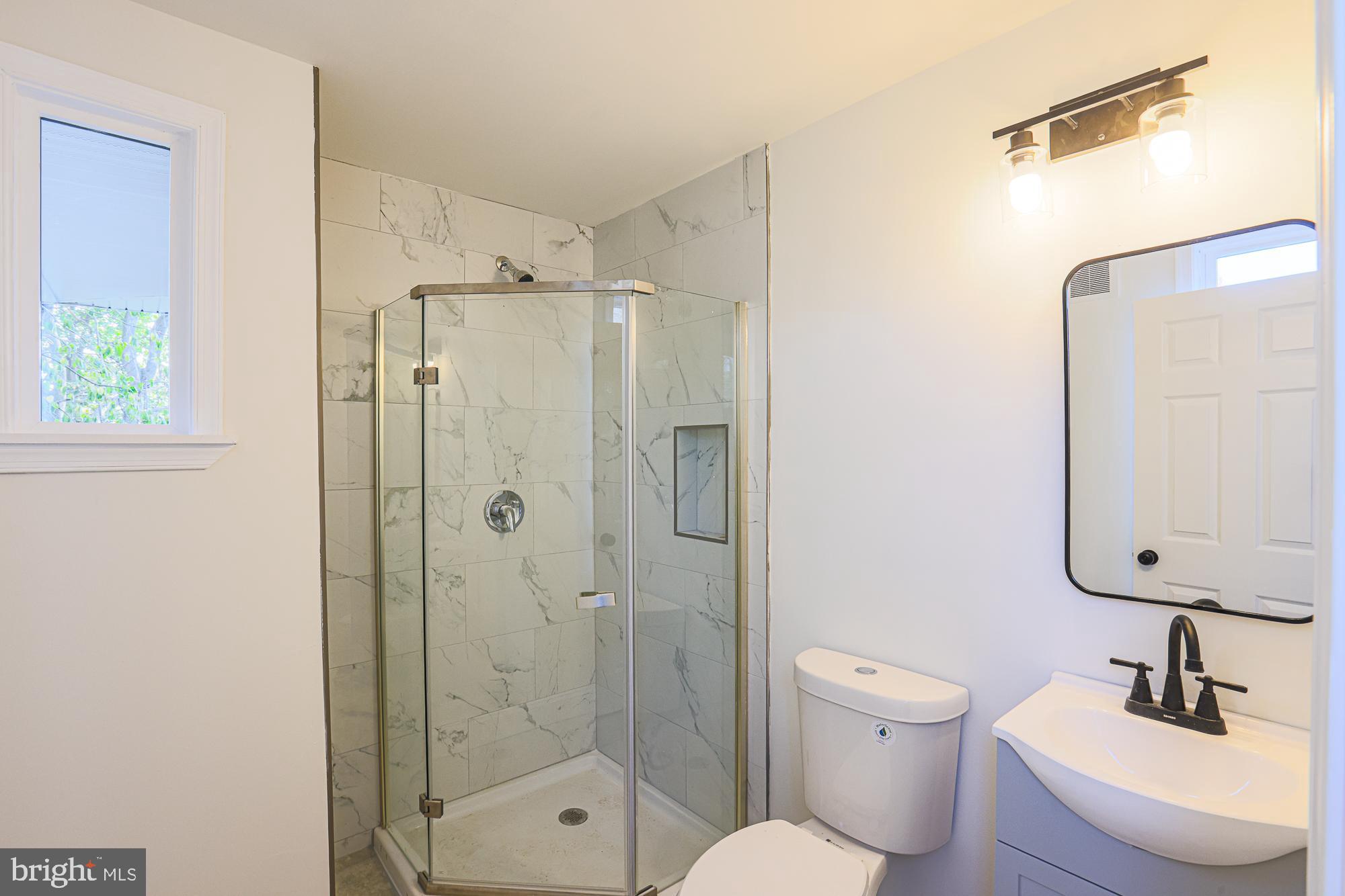 2606 Queen Anne Road Baltimore, MD 21216 - Photo 74 of 92 a bathroom with a shower sink vanity mirror and toilet